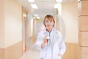 Caucasian senior woman doctor with stethoscope standing in hospital photo