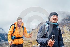 Caucasian and Sherpa men backpackers with trekking poles together hiking and enjoying Mera peak climbing acclimatization walk