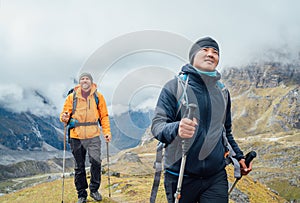 Caucasian and Sherpa men backpackers with trekking poles together hiking and enjoying Mera peak climbing acclimatization walk