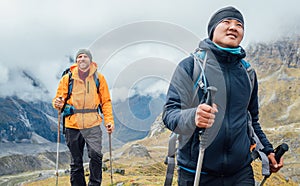 Caucasian and Sherpa men backpackers with trekking poles together hiking and enjoying Mera peak climbing acclimatization walk