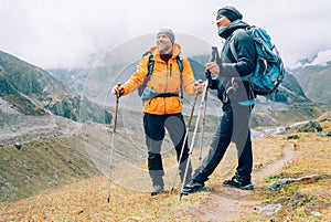 Caucasian and Sherpa men with backpacks with trekking poles together smiling enjoying Mera peak climbing acclimatization walk