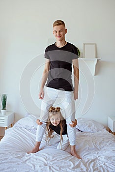Caucasian siblings - teenager boy brother and little girl sister in bedroom modern loft interior.