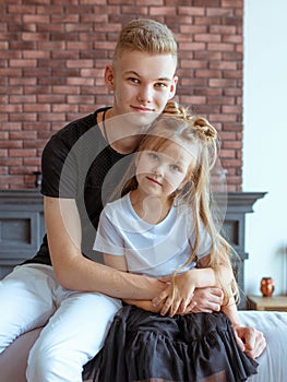 Caucasian siblings - teenager boy brother and little girl sister laying holding hands