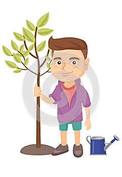 Caucasian smiling boy planting a tree.