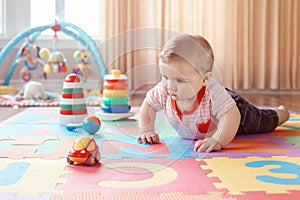 Caucasian smiling child boy with blue eyes lying on floor in kids children room