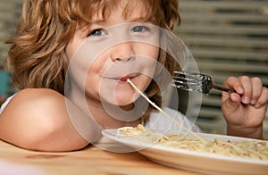 Caucasian smiling child eating pasta, spaghetti, portrait close up. Kids face.