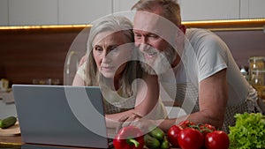 Caucasian smiling couple adults old 70s mature woman man middle-aged spouses laughing happy elder family using laptop in