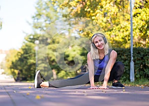 Caucasian smiling grownup woman doing exercise outdoor in fall in urban park, selective focus