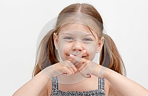 Child holding crossed fingers on mouth photo