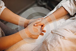 Caucasian spa worker massaging the patient`s hand and preparing it for next procedure photo