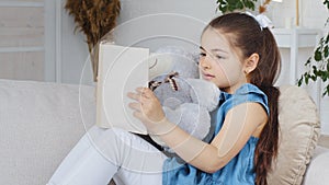 Caucasian spaniard school girl child kid daughter pupil sitting on couch sofa at home in living room interior hugging