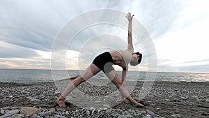 Caucasian sportive woman practicing yoga at seashore of tropic ocean. Healthy lifestyle. Fitness concept.