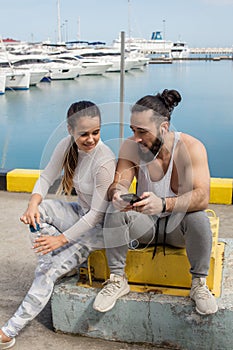 Couple listening to music together using one earphones sitting on pier
