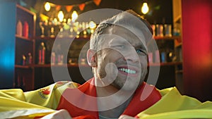 Caucasian sports fan waving Spanish flag in pub, displeased about team defeat