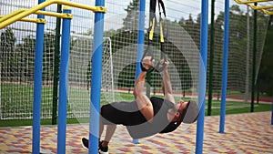 Caucasian sportsman doing pull ups exercise using rubber belt to force strenth of workout outdoors