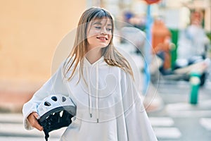 Caucasian sporty teenager girl smiling happy holding bike helmet at the city