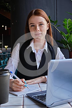 caucasian student sitting at table of cafe, studying with laptop, doing homework