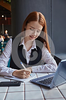 caucasian student sitting at table of cafe, studying with laptop, doing homework