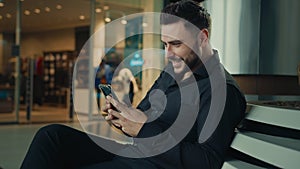 Caucasian stylish man in black suit successful businessman customer sit at shopping mall using mobile phone apps make