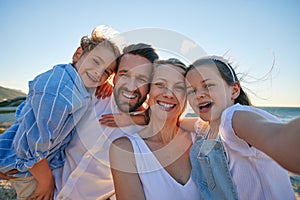 Caucasian taking a selfie on the beach. Happy family on holiday taking a photo by the ocean. Portrait of a cheerful