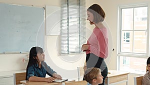 Caucasian teacher walking around classroom while explain classwork. Pedagogy.