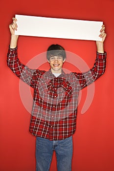 Caucasian teen boy holding blank sign above his head.