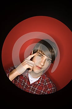 Caucasian teen boy pointing to his head.