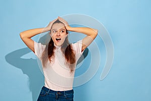 Caucasian teen girl portrait isolated on blue studio background