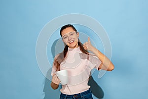 Caucasian teen girl portrait isolated on blue studio background