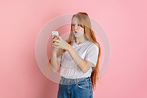Caucasian teen girl`s portrait  on coral pink studio background.