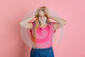 Caucasian teen girl`s portrait isolated on coral pink studio background.