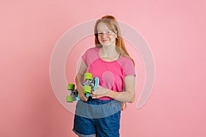 Caucasian teen girl`s portrait isolated on coral pink studio background.
