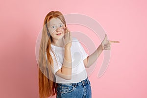 Caucasian teen girl`s portrait isolated on coral pink studio background.
