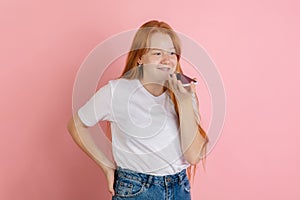 Caucasian teen girl`s portrait isolated on coral pink studio background.