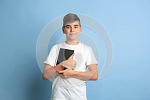 Caucasian teen`s portrait isolated on blue studio background