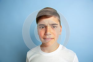 Caucasian teen`s portrait isolated on blue studio background