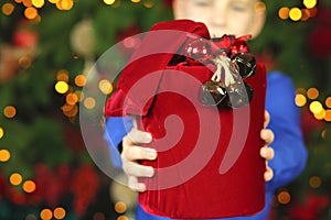 Caucasian teenage boy in a blue shirt sitting with a huge red box with gifts in a New Year`s interior. New Year`s and Christmas.