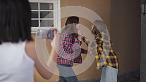 Caucasian teenage girl steaming online fight of angry classmates outdoors. Shooting over shoulder of blurred teenager