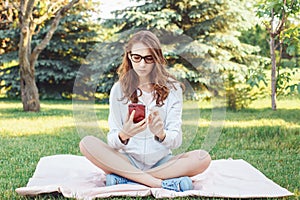 Caucasian teenage girl talking over cell mobile phone outside in park Caucasian teenage girl making selfie photo with her phone