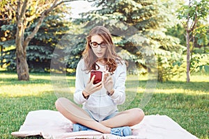 Caucasian teenage girl talking over cell mobile phone outside in park Caucasian teenage girl making selfie photo with her phone