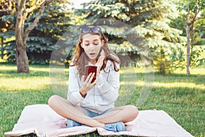 Caucasian teenage girl talking over cell mobile phone outside in park Caucasian teenage girl making selfie photo with her phone