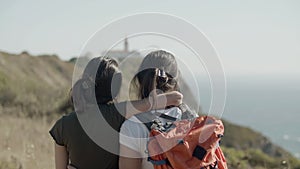 Caucasian teenaged girls standing at cliff, admiring sea view.