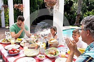 Caucasian three generation family praying during a lunch in the garden