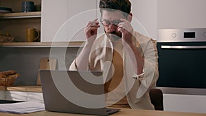 Caucasian tired exhausted man rubbing eyes feeling eyestrain discomfort put on glasses working laptop online distant job