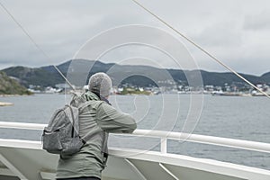 Caucasian tourist standing on the deck on a ferry watching the arrival in BodÃ¸, photo