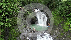 Caucasian tourists swimming in the tropical waterfall in Costa Rica.