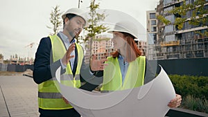 Caucasian two people colleagues coworkers builders architects engineers woman and man in helmets hardhats and vests