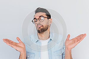 Caucasian unsure man make gestures doubtfully with hands with copy space. Uncertain young stylish stubble male with trendy round