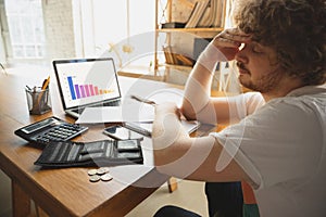 Caucasian upset and despair man watching financial and economical graphs going down during coronavirus quarantine