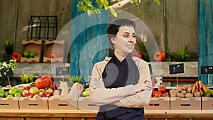 Caucasian vendor standing with amrs crossed at farmers market stand